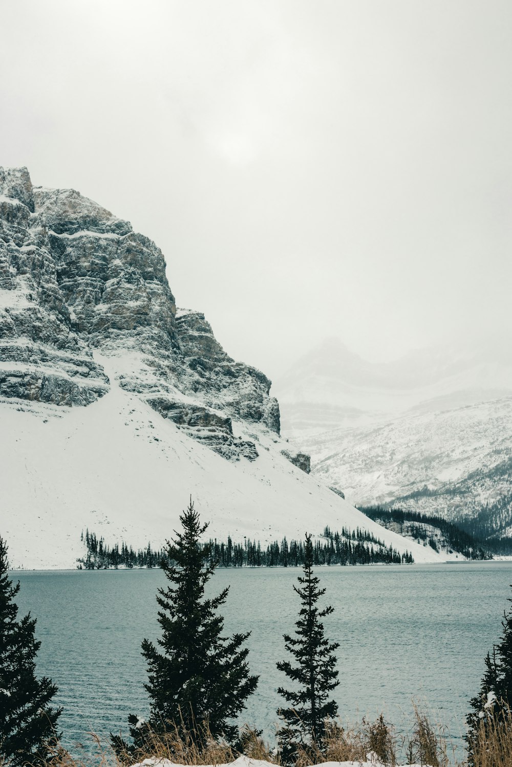 a snow covered mountain with a lake in the foreground