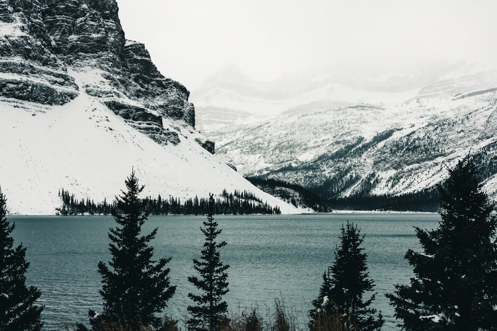 a lake surrounded by snow covered mountains and evergreen trees