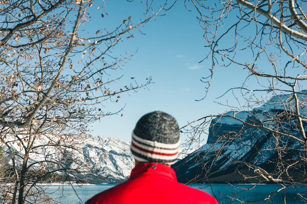 a man in a red jacket looking out over a body of water