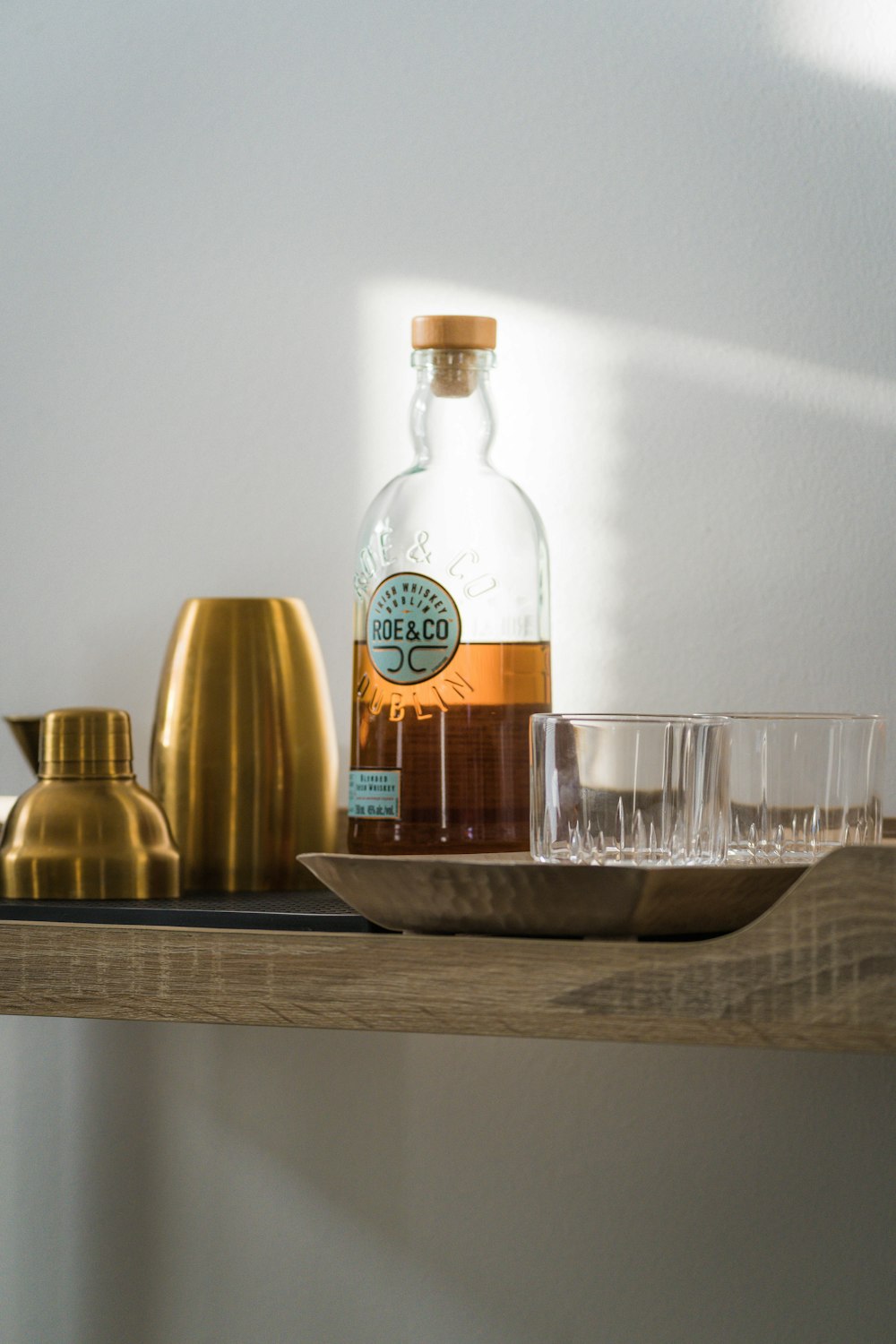 a shelf with a bottle of alcohol and glasses on it