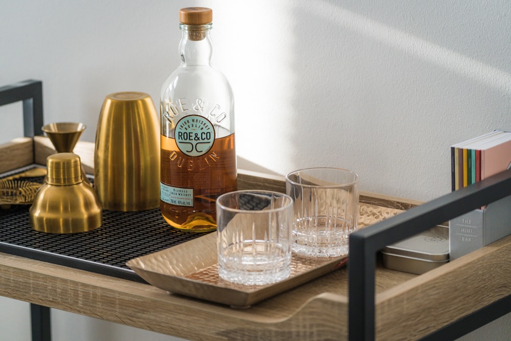 a bottle of alcohol and two glasses on a tray