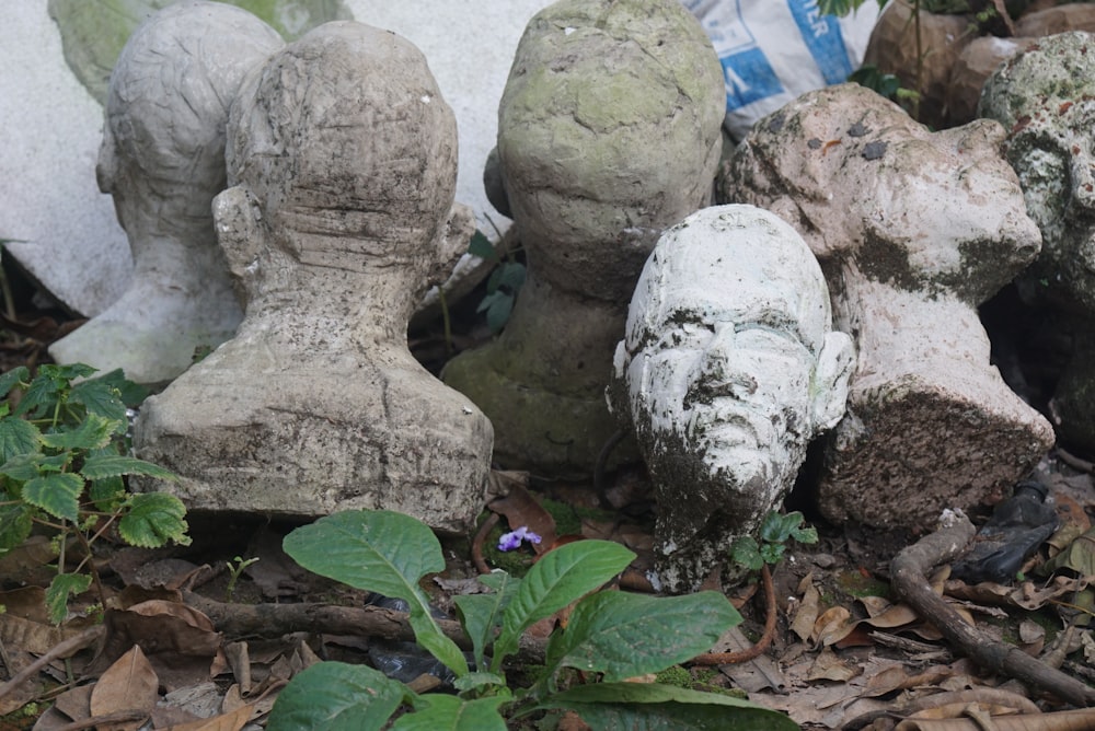 a group of stone statues sitting on top of a leaf covered ground