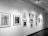 A gallery wall features a series of framed black and white sketches and drawings. The collection includes various portraits and studies of human figures in different poses, with some sketches showing detailed expressions and postures.