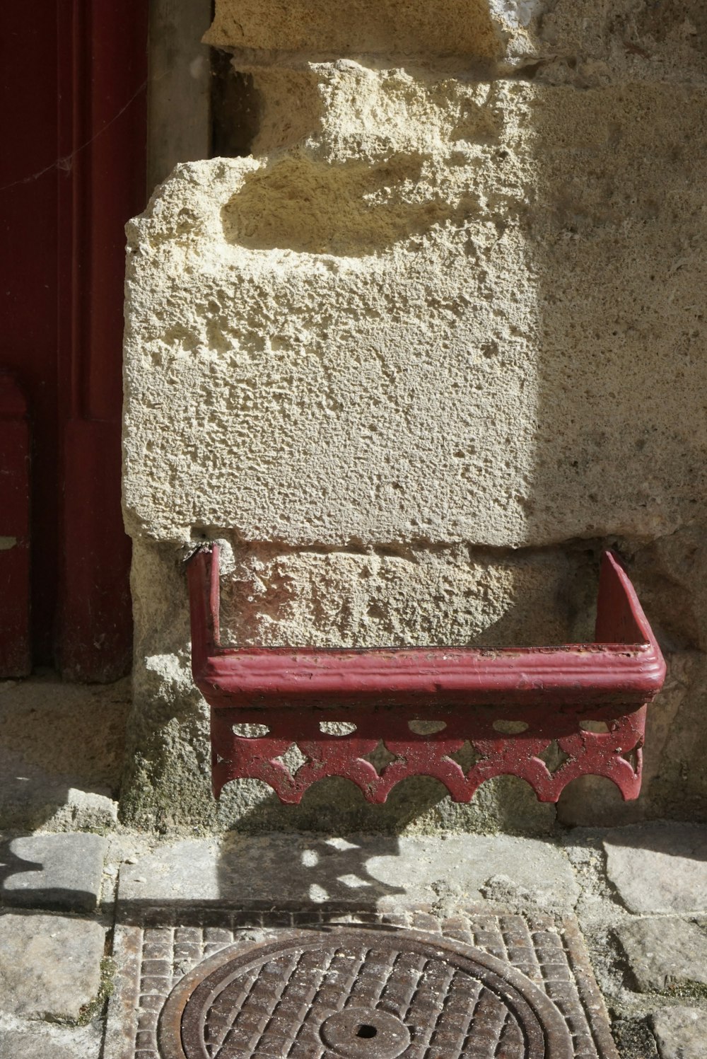 a red bench sitting next to a stone wall