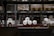 A warehouse shelf filled with packaged rolls of material. The rolls are arranged neatly on metal racks, surrounded by boxes and pallets. The lighting is dim, creating a sense of depth and storage abundance.
