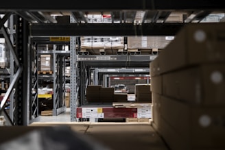 Industrial warehouse showing rows of corrugated boxes stacked on pallets ready for shipment.