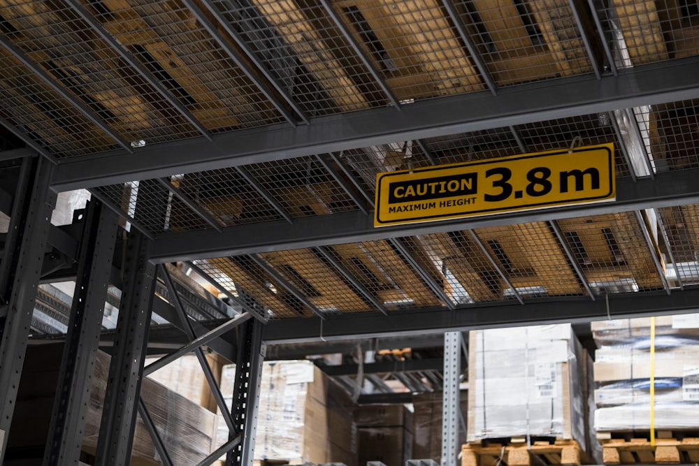 a yellow and black sign hanging from the ceiling of a warehouse