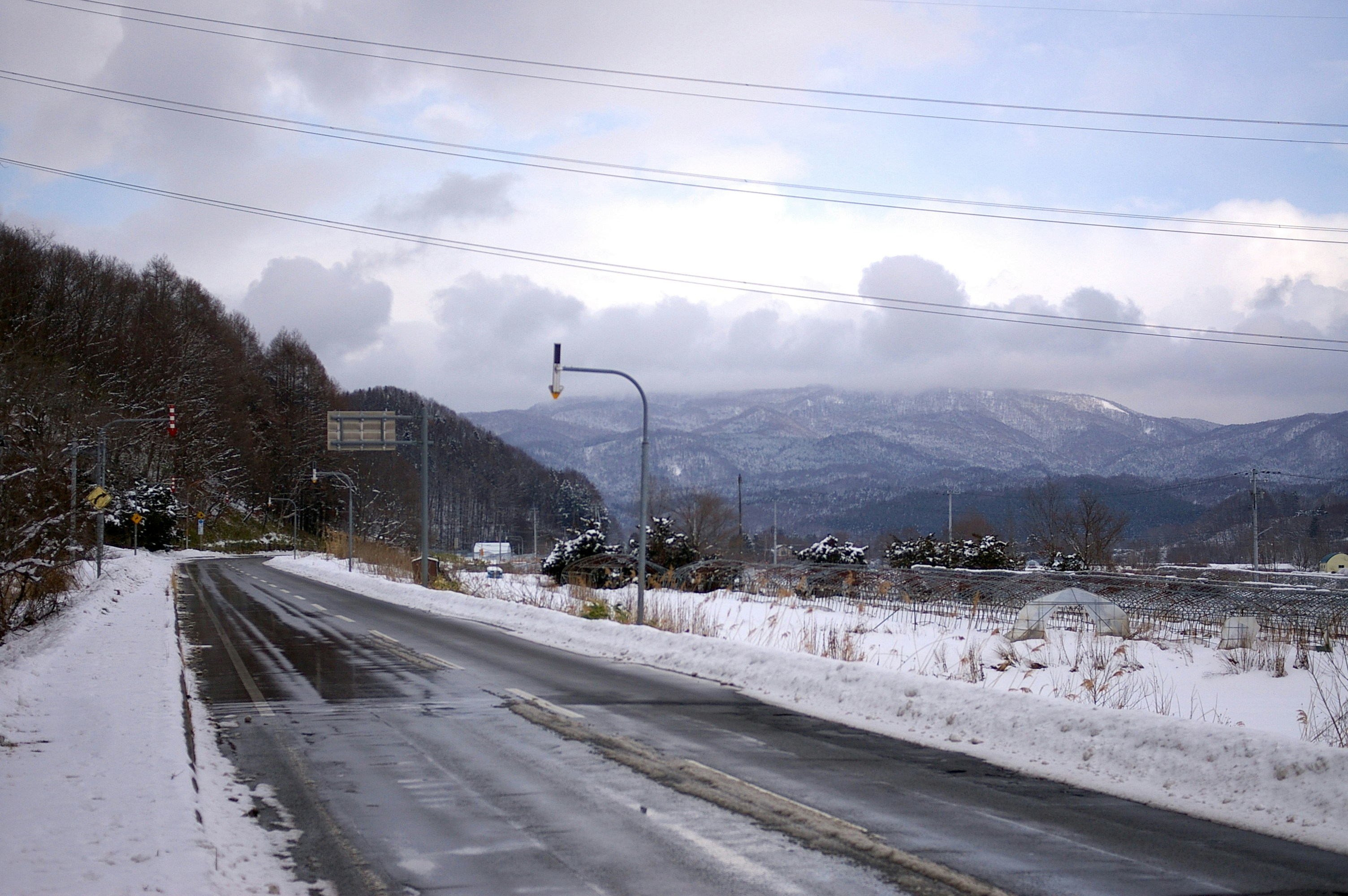 a snow covered road with mountains in the background