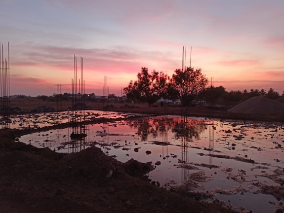 Civil engineer reviewing structural plans at a construction site during sunset.