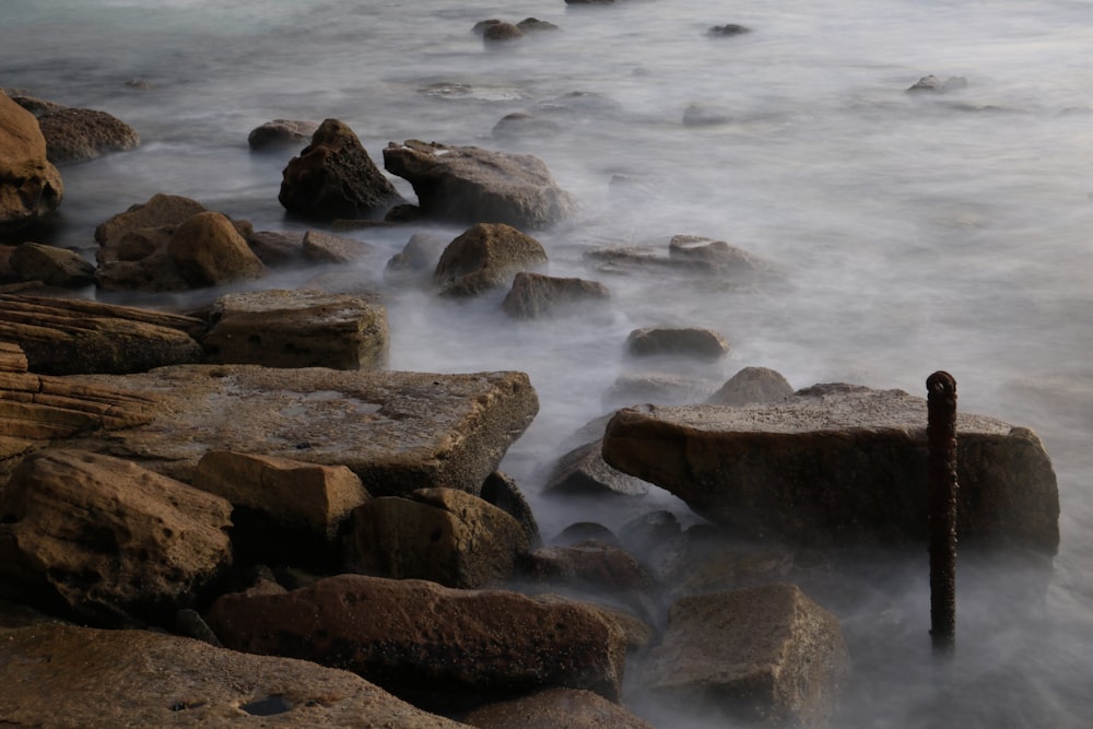 a long exposure photo of the ocean and rocks