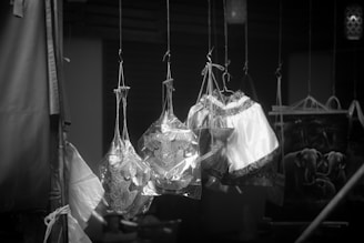 Hanging traditional puppets encased in plastic are prominently displayed. These intricately crafted figures have detailed costumes with distinctive patterns. The background contains additional hanging items and what appears to be a textile with an elephant design.