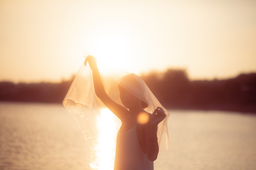 uma mulher com um véu na cabeça em pé na frente de um corpo de água