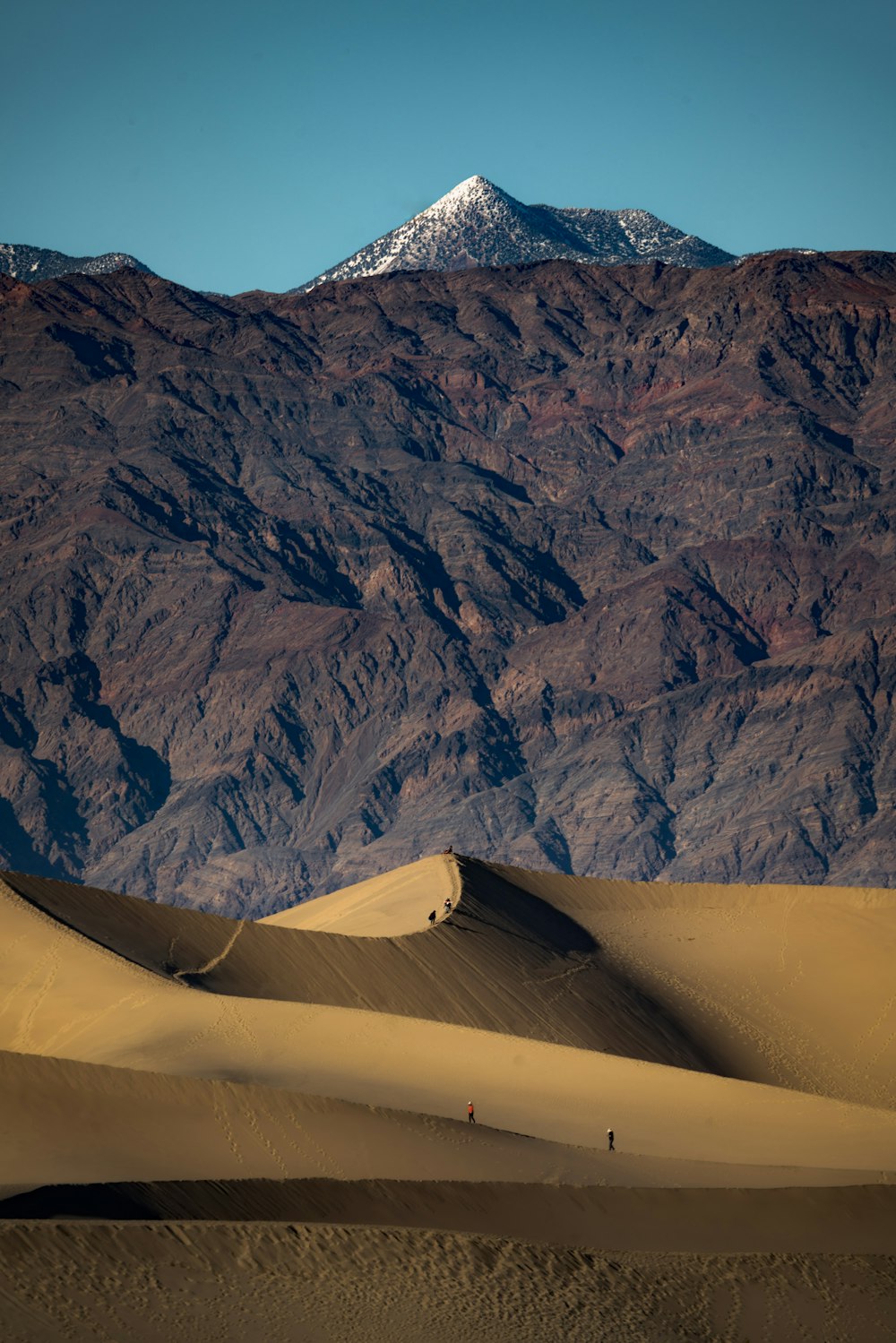 a mountain range in the distance with sand dunes in the foreground