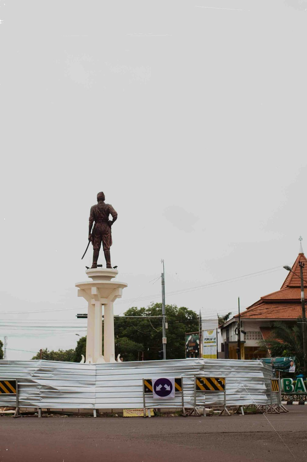 a statue of a man standing on top of a white pillar