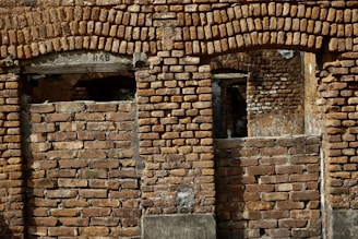 A large brick wall with patches showing exposed rustic bricks.