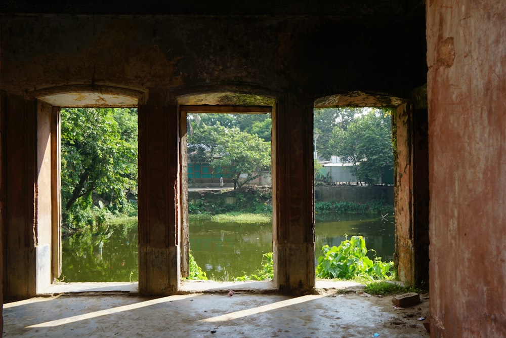 a room with three windows and a view of a pond