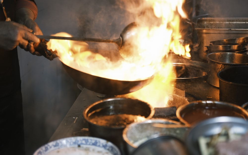 a person cooking food in a wok on a stove