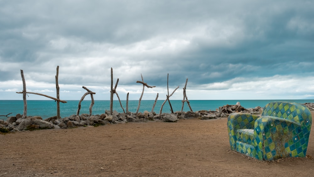 Una silla sentada en la cima de una playa de arena junto al océano