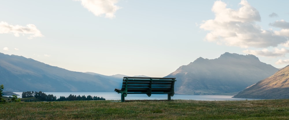 a bench sitting on top of a lush green hillside