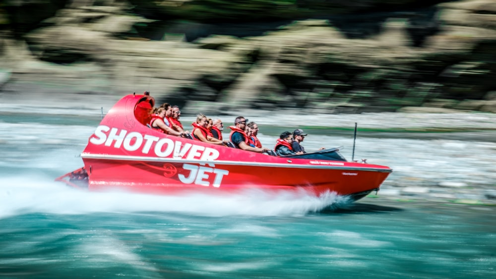 a group of people riding on the back of a red boat