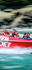 a group of people riding on the back of a red boat