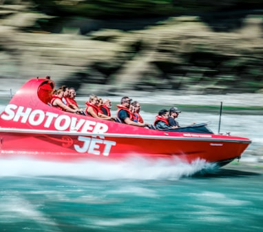 a group of people riding on the back of a red boat