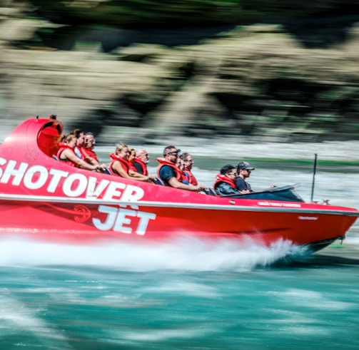 a group of people riding on the back of a red boat