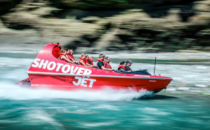 a group of people riding on the back of a red boat