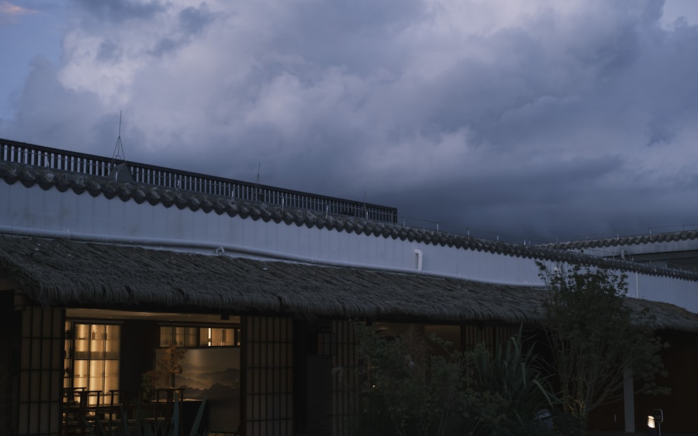 a building with a thatched roof and a dark sky in the background