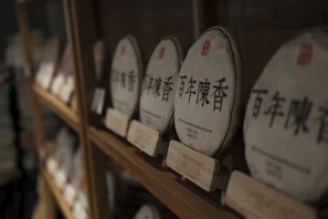 Rustic wooden shelf displaying various pu-erh tea cakes wrapped in paper
