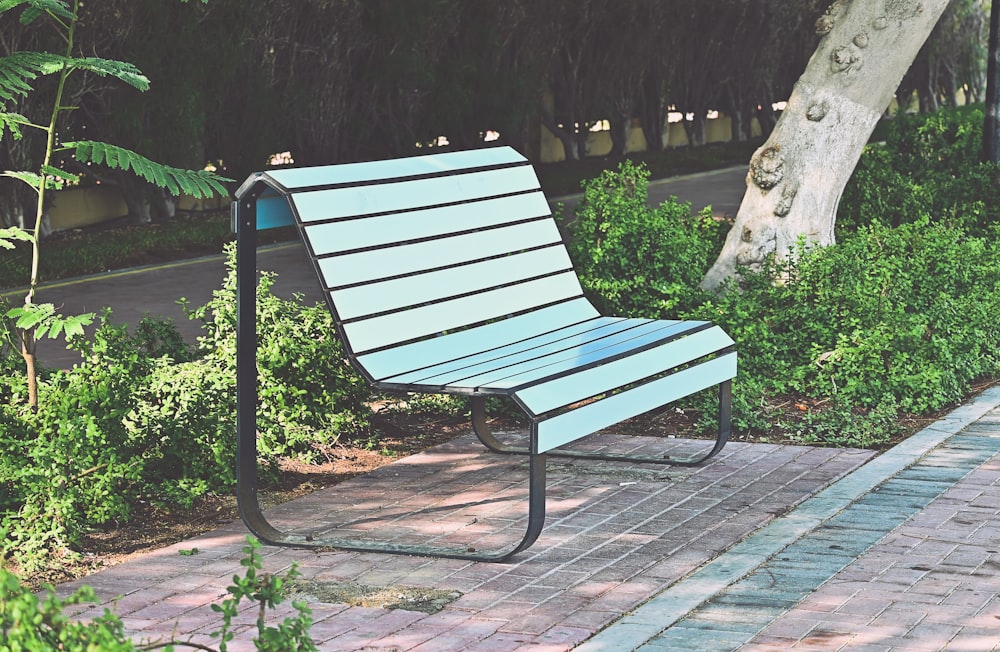 a blue and black bench sitting on a brick walkway