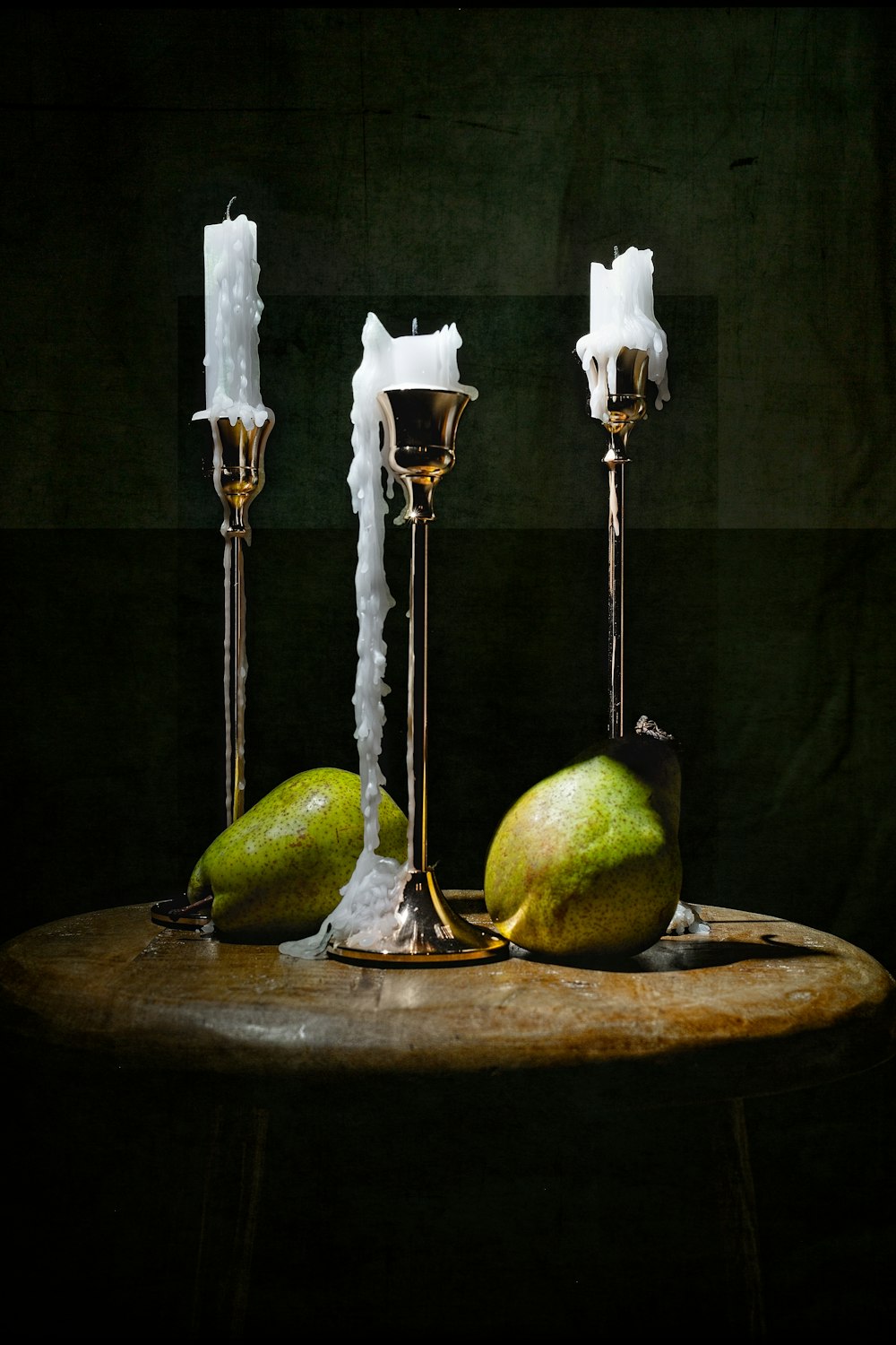 a table topped with three candles and two pears