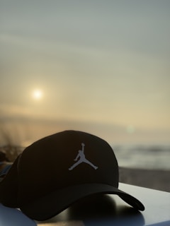 A rugged fishing hat with 50x50 outdoors logo resting on weathered driftwood by a calm Texas bayou at sunrise.