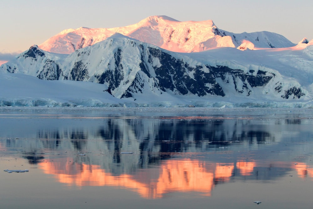 a mountain covered in snow next to a body of water