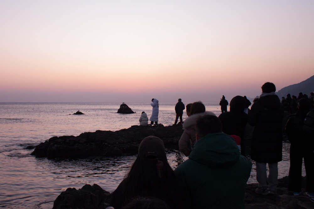 a group of people standing on top of a rocky beach