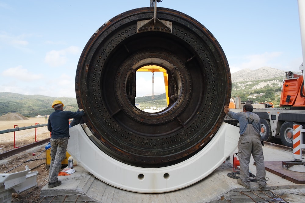 a couple of men standing next to a giant object