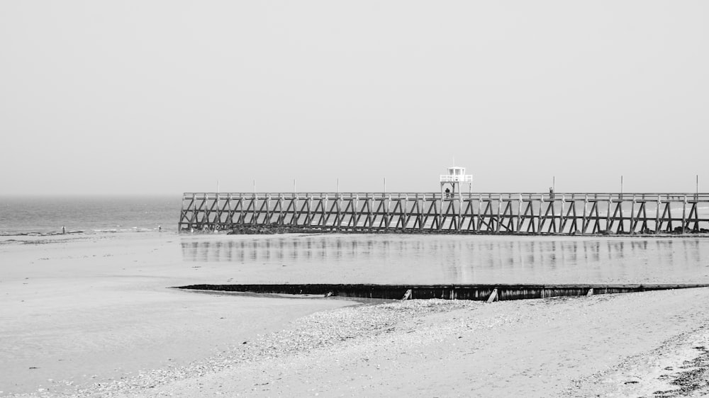 a black and white photo of a pier on the beach