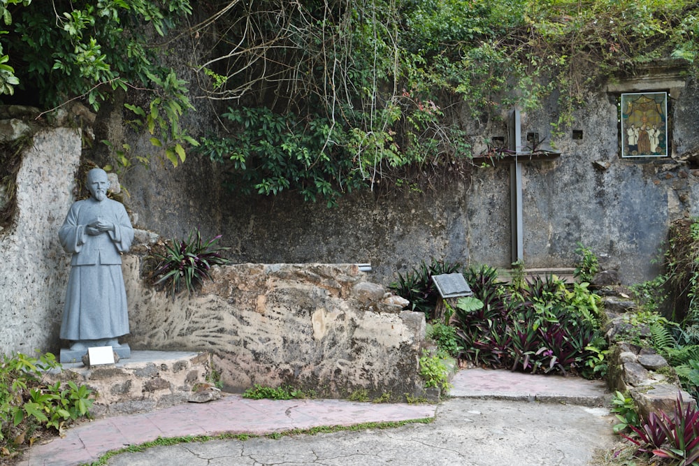 a statue of a woman standing next to a stone wall