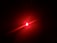 A bright red light source emitting beams and creating a glowing effect against a dark background.
