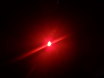 A bright red light source emitting beams and creating a glowing effect against a dark background.