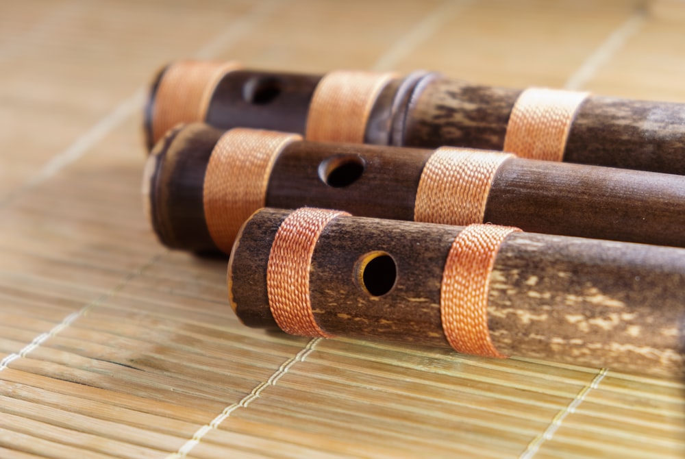 a close up of three wooden pipes on a bamboo mat