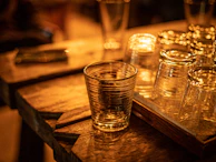 Friends clinking cocktail glasses over a dark wood table lit by golden candlelight.