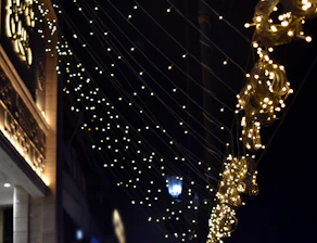 Close-up of elegant Christmas lights wrapped around windows and roof edges, glowing warmly.