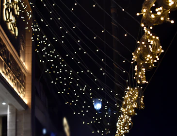 Close-up of elegant Christmas lights wrapped around windows and roof edges, glowing warmly.