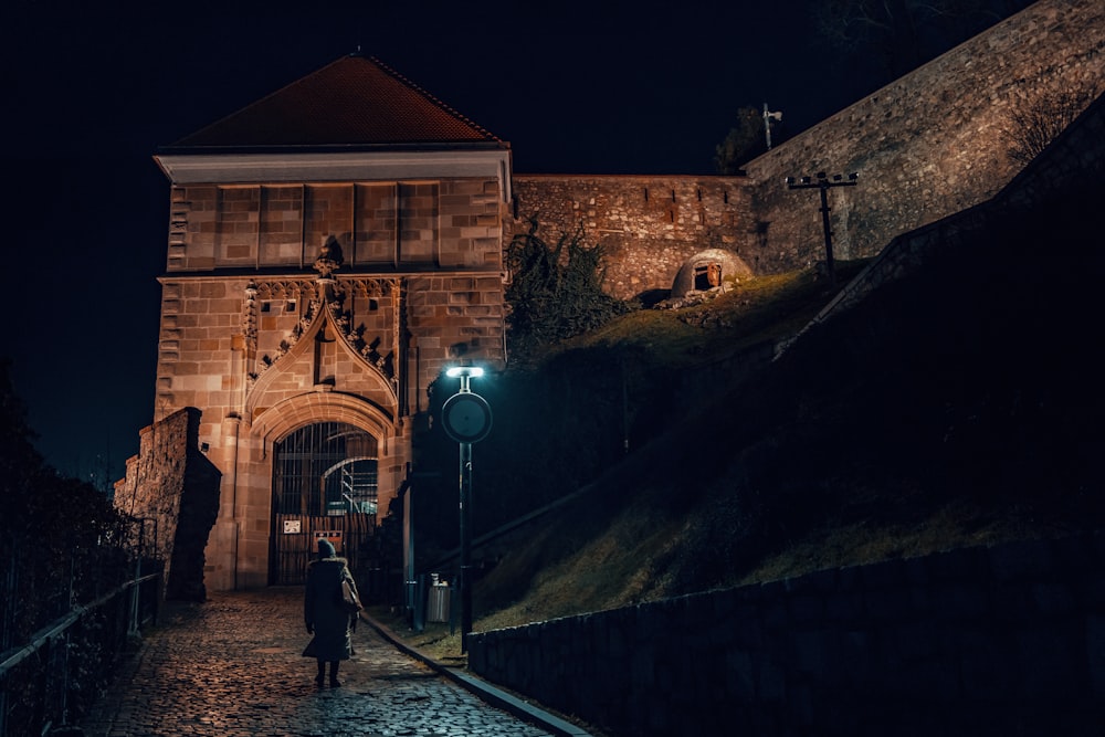 a person walking down a cobblestone street at night