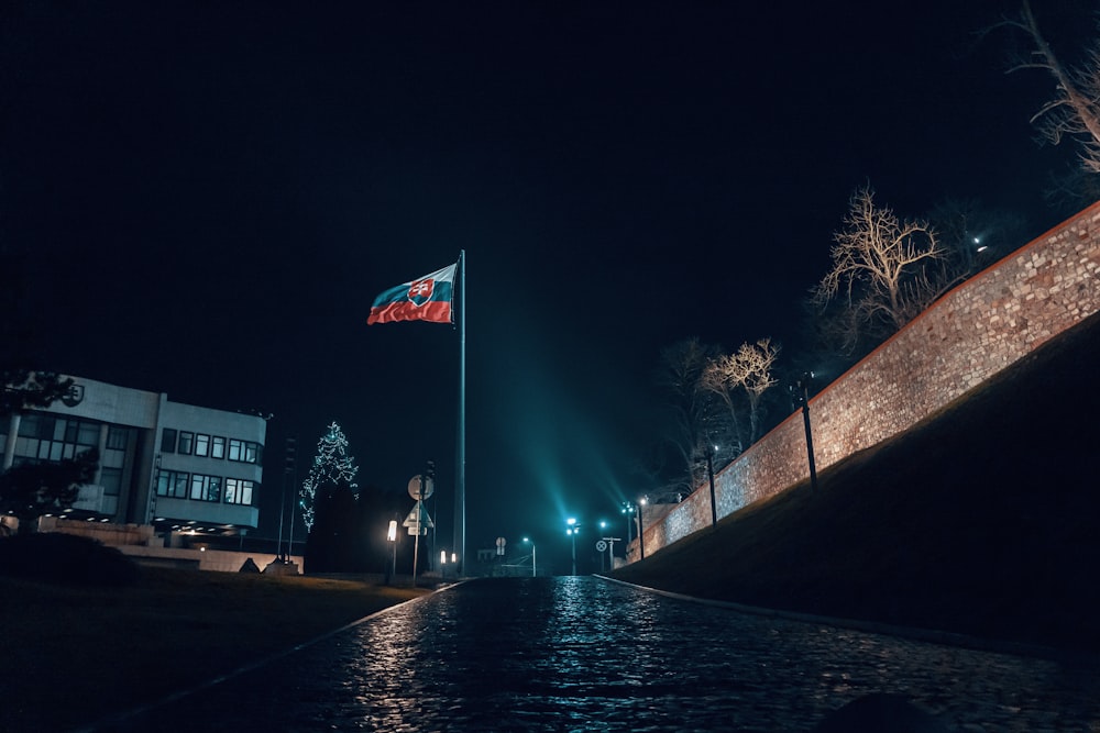 a street at night with a flag on a pole