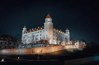 a castle lit up at night with people walking around