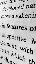 A close-up view of black text printed on a white textured paper. The image emphasizes the words 'features', 'Supportive', and 'awakening' among others, with visible texture of the paper adding a tactile dimension.