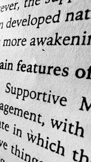 A close-up view of black text printed on a white textured paper. The image emphasizes the words 'features', 'Supportive', and 'awakening' among others, with visible texture of the paper adding a tactile dimension.