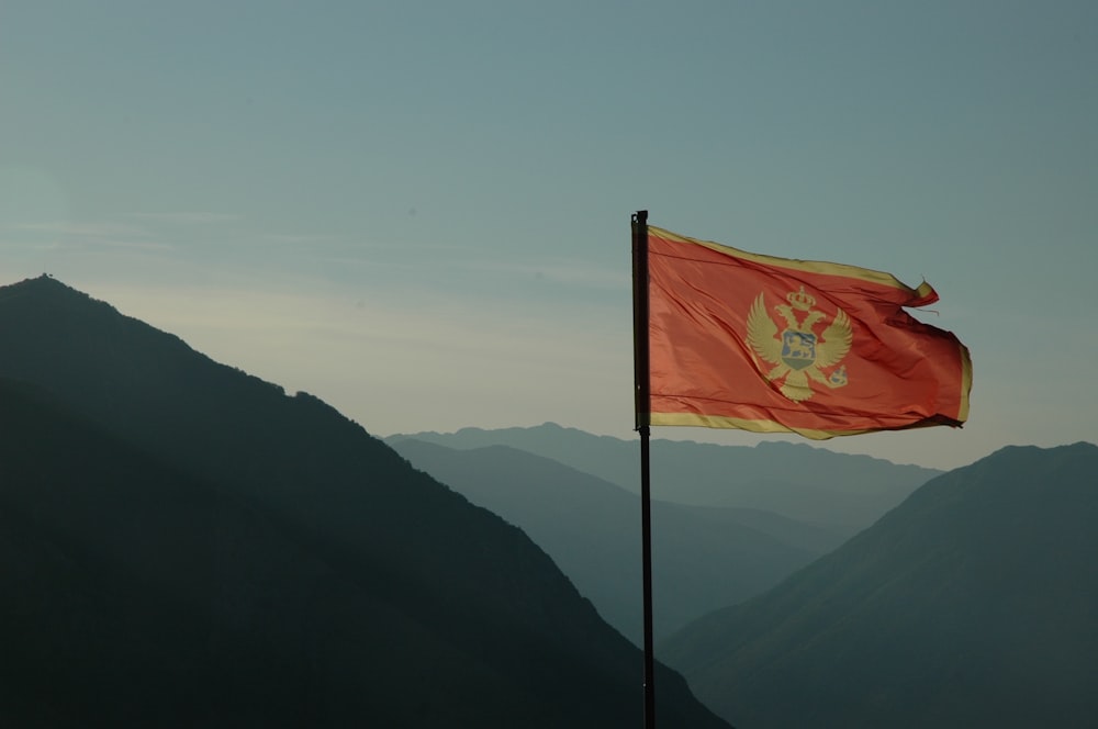 a flag on top of a mountain with mountains in the background